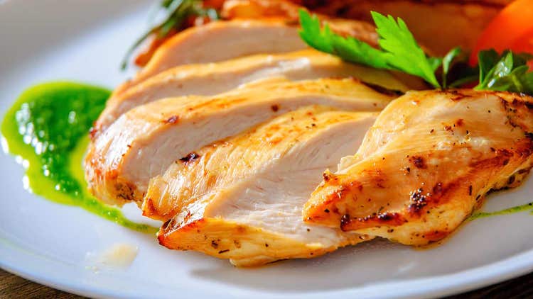 Sliced grilled chicken breast served with sauce, emphasizing yield and juiciness.